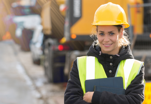 Construction worker holding a tablet on a construction site.